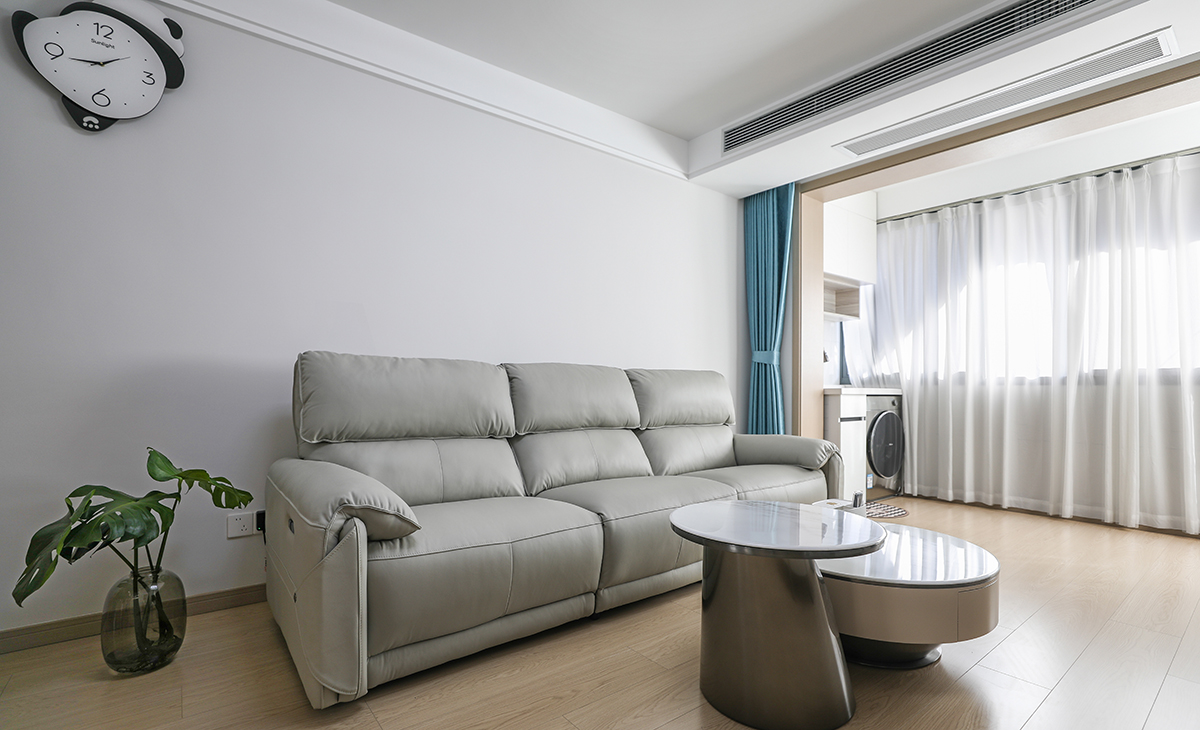 沙发背景浅灰色涂料，蓝色的窗帘，色调上墙面涂料和纱帘用浅色，沙发用浅灰色，深浅搭配的错落有致，既温馨又简洁。