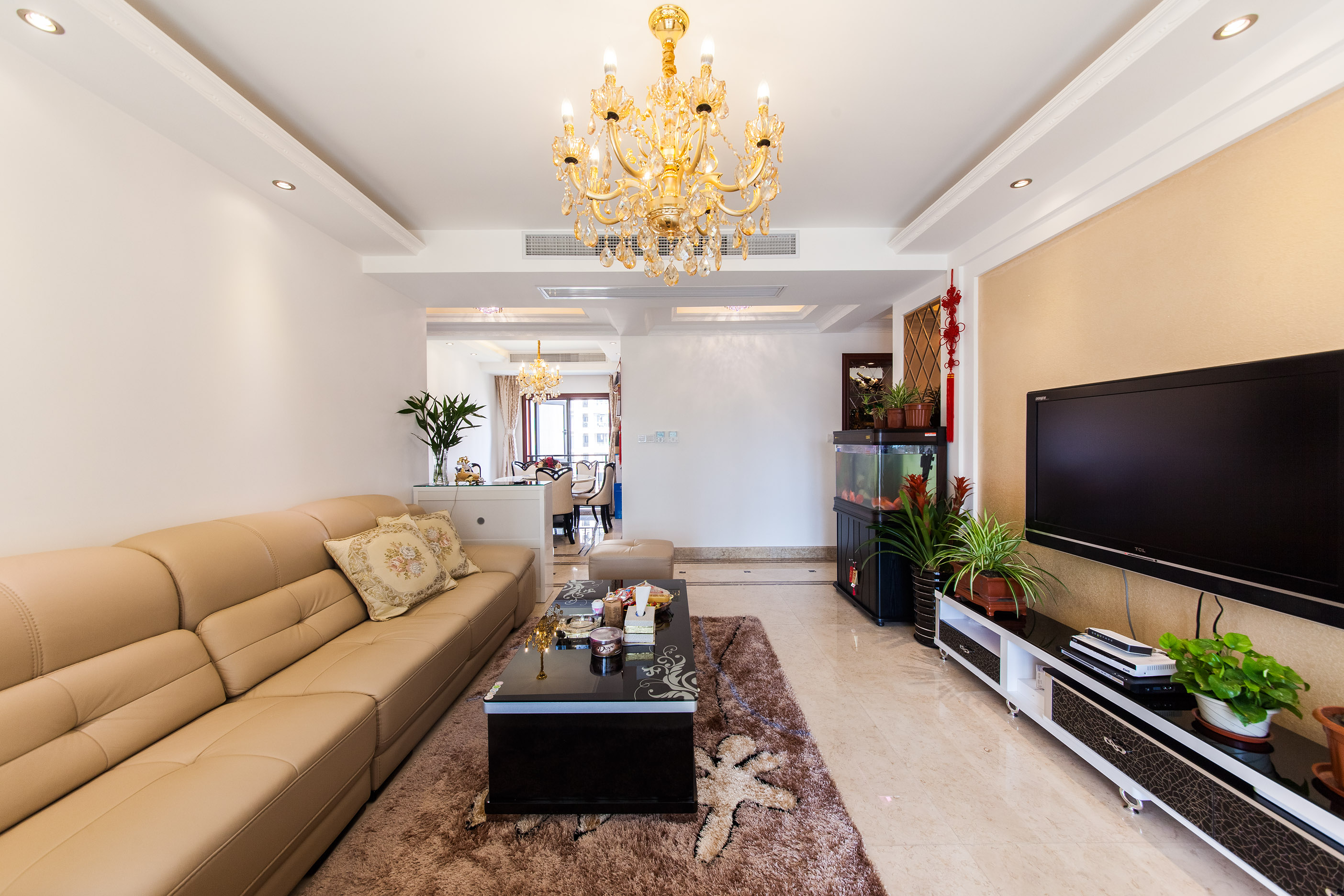 客厅采用黄色的皮质沙发，与电视背景墙的色调前后呼应，深色的地毯表现的更加简洁大方，清新的绿植表现的更加生机盎然。
