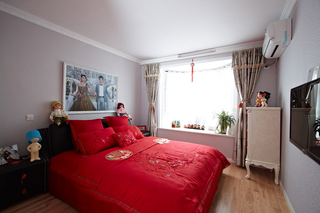 温馨舒适的卧室环境彰显结婚的喜悦，用浅色的地板红色的床单，形成一种呼应，舒适的飘窗，不影响采光的同时使得屋内的光线、空间整体放大，给新婚的主人带来清新舒适的享受体验。
