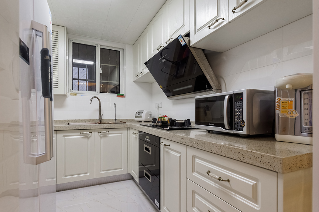 厨房空间不是很大，色彩上采用米白色的模压板，加上白色的墙面砖，使得空间得以延伸，看上去显得更宽敞。
