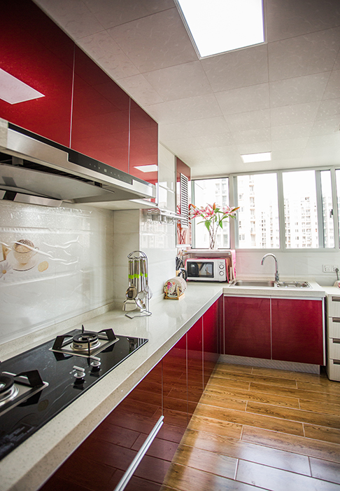 厨房采用红色系的精钢板系列门板，加上白色的墙面砖，使得空间得以延伸，看上去显得更宽敞
