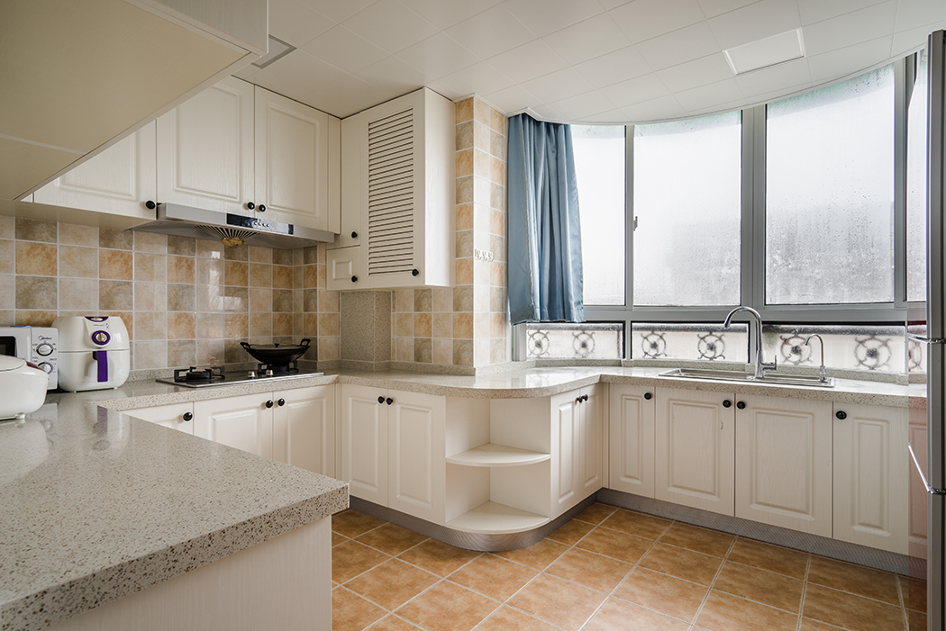 厨房墙面用暖色的小格子砖加上白色整洁的厨柜来修饰，使人很容易就爱上这宽敞、明亮的厨房。
