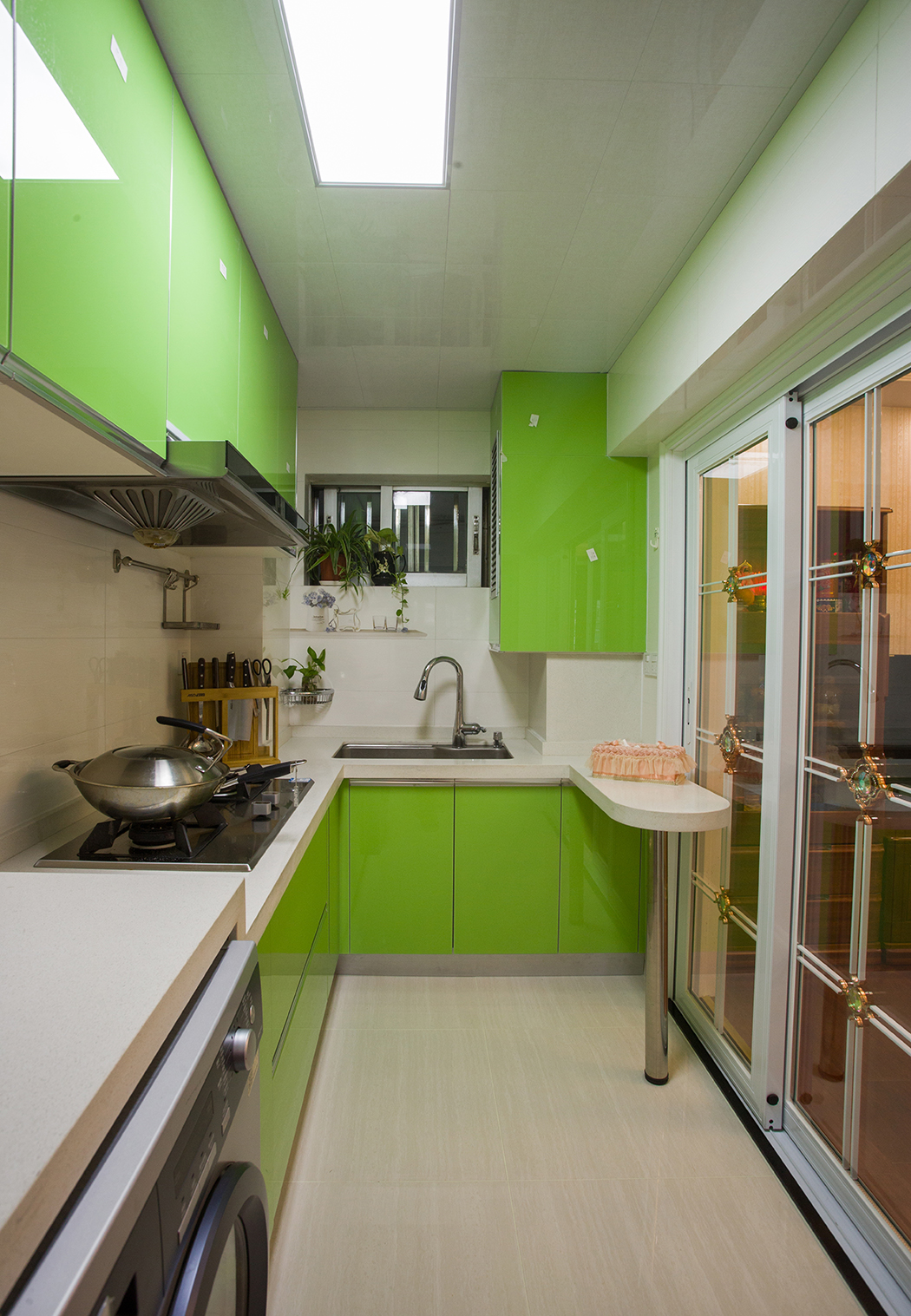 厨房橱柜颜色大胆选用了苹果绿色，凸显美式田园风格的清新自然，生机盎然，厨房以功能实用为主，L型橱柜加小吧台的设计大大提升厨房的实用性，橱柜内嵌的冰箱和烘干机，都使空间得到充分利用。
