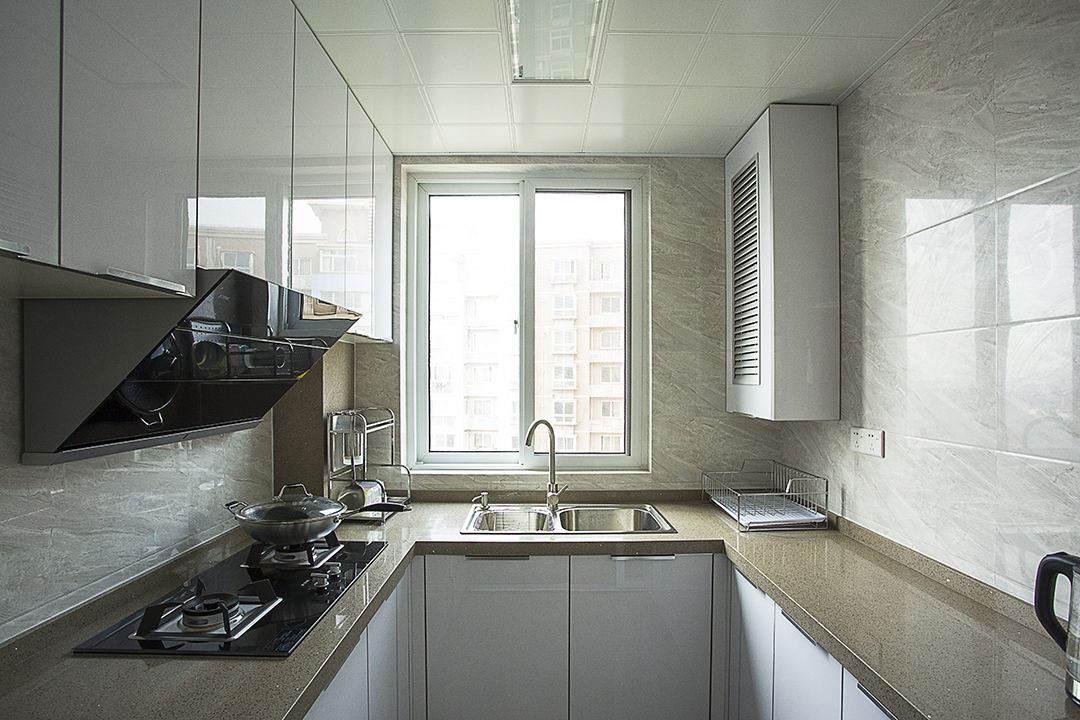 厨房间的设计风格并没有沿用整体的新中式的理念，而是采用了更加直接实用的隐形精钢板作为主体，简约的同时又便于打理。灰色的瓷砖搭配白色的橱柜，凸显了更多的层次。
