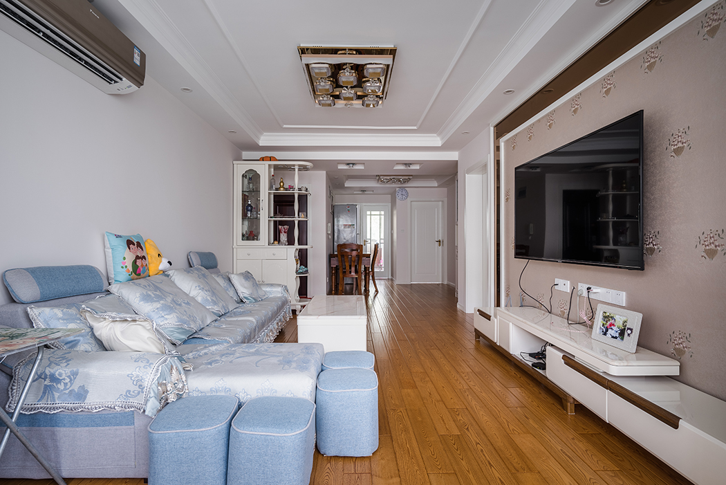 客厅浅色调的墙面，搭配蓝色的沙发，再配以橡木色的地板，整体感觉朴素优雅，作为日常生活最多的区域，诠释了户主的生活品味。
