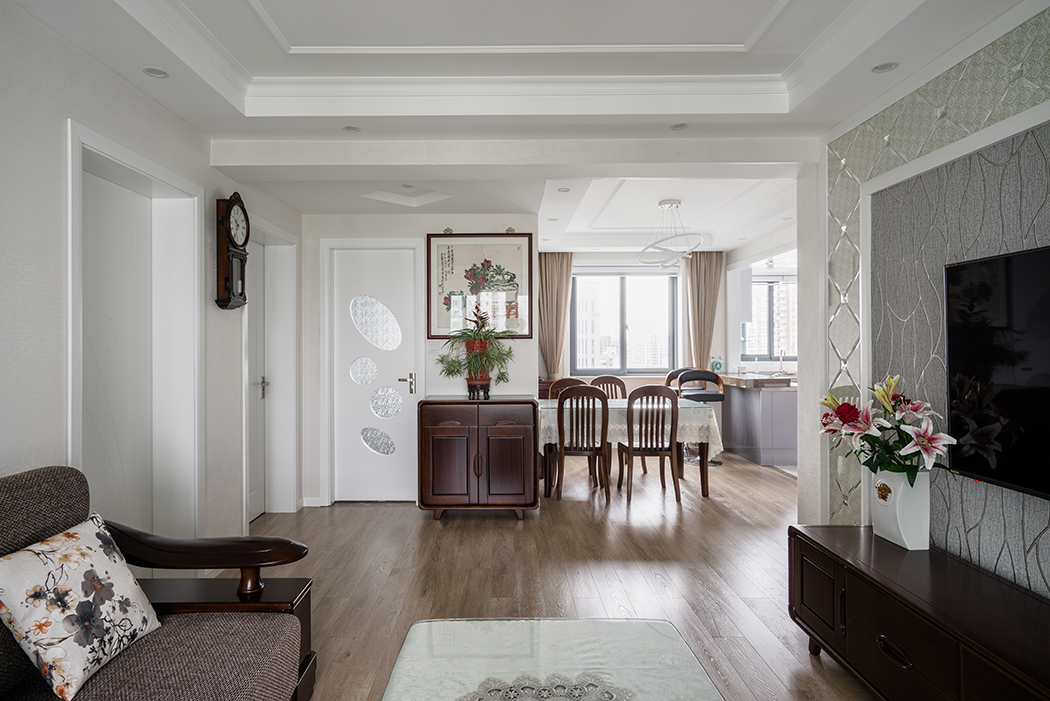 客厅的背景采用了白色木线条，素色软包加壁纸，米色的窗帘，搭配深色的家具赋予空间平衡之美。
