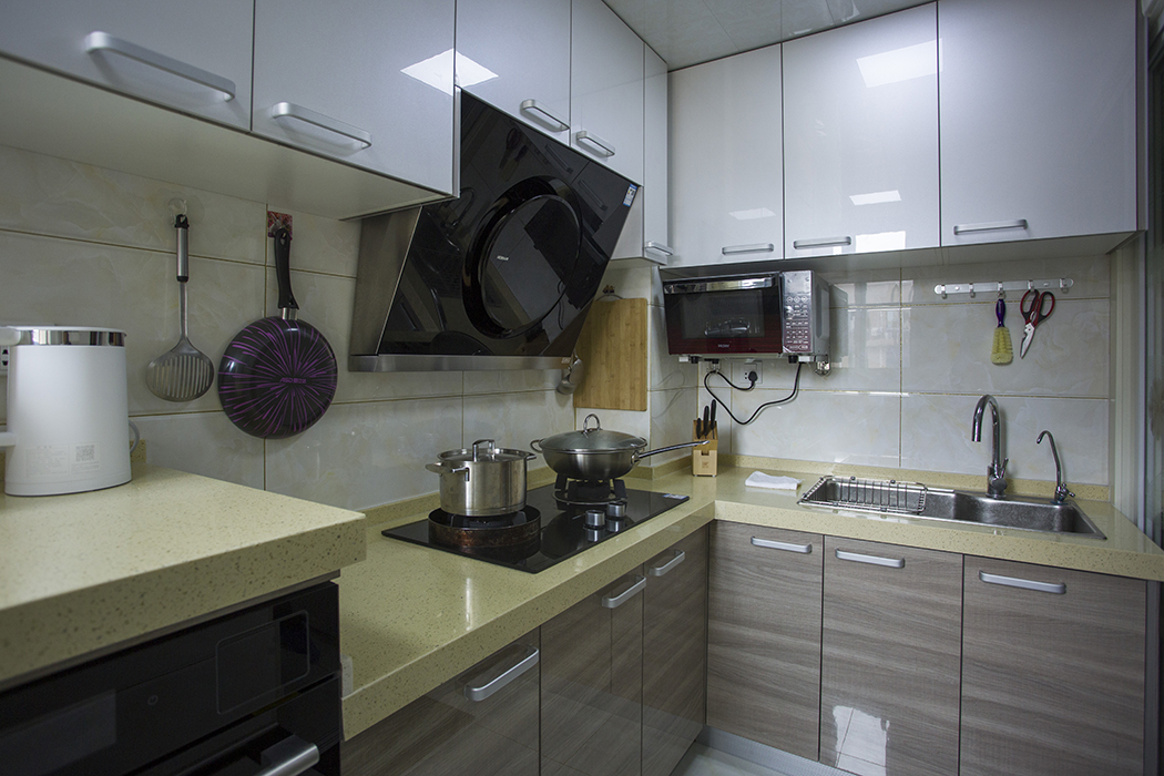 厨房的格局改变之后更加明亮开阔，L型橱柜简洁大方，白色上柜，黄色台面，深色下柜，层次分明，极具生活气息。