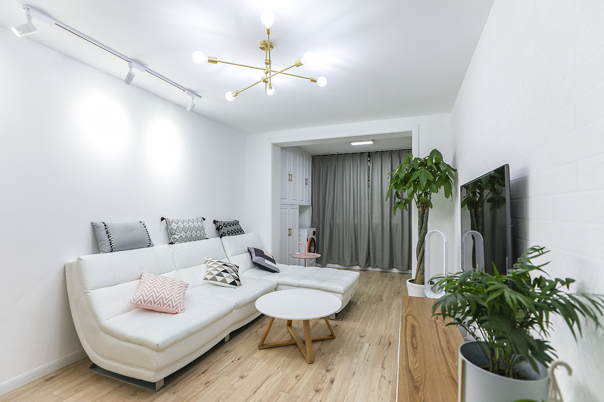客厅和阳台连为一体，使空间宽阔很多，米白色现代风的贵妃沙发配上实木电视柜和绿植，把空间打造成健康、温馨、时尚干净的会客区。
