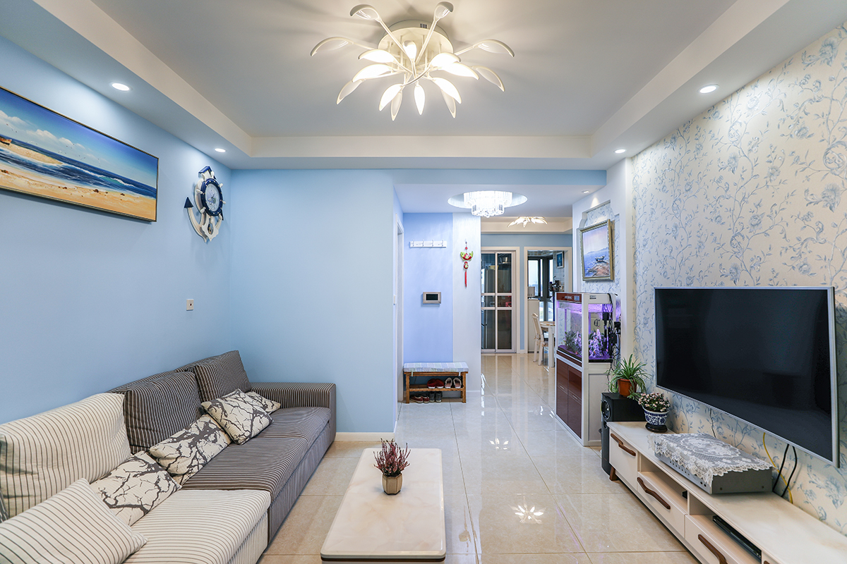 客厅墙面整体采用蓝色乳胶漆，和白底蓝花的电视墙相得益彰，灰色和米黄色条纹的布艺沙发成为蓝色沙发墙的一大亮点。
