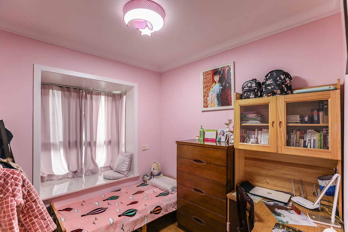 女儿房整体采用浪漫温馨的粉红色，小床紧靠飘窗，床边的五斗橱和转角书桌，在小姑娘的独立小天地里，丰富又充实。
