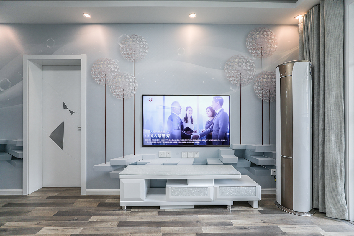客厅整体风格采用蓝色墙面涂料和灰白色系的地板合理搭配，电视柜采用白色的搭配，使得整体空间的简洁，吊顶采用台阶式吊顶加以简单线条，配以中性色的射灯，使得光线得以明朗，视觉得以解放。
