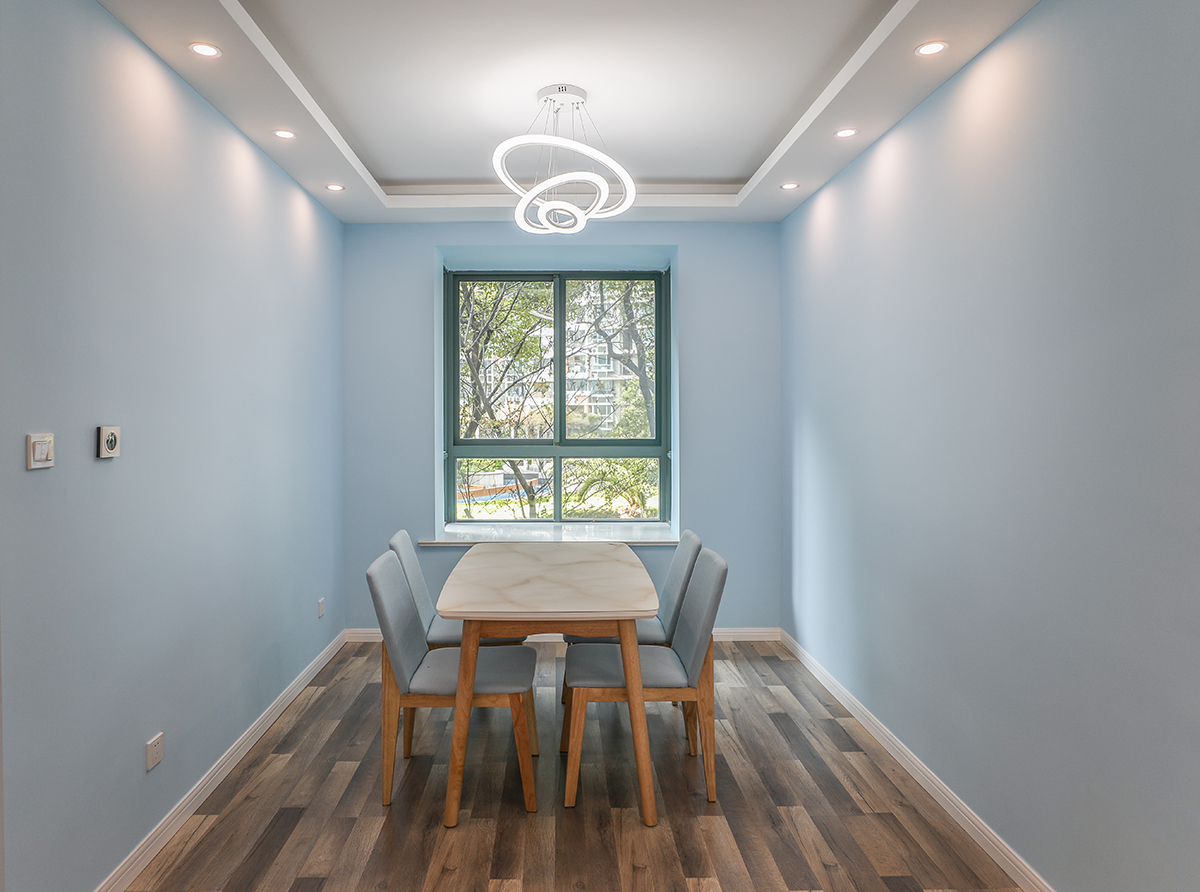 餐厅采用了木色的餐桌，使得空间非常的简洁清爽，造型的无意中给餐厅增添一处亮点，蓝色的墙面和木纹的地板加以白色的木门使得简约元素非常的充足，得以空间的最大化。
