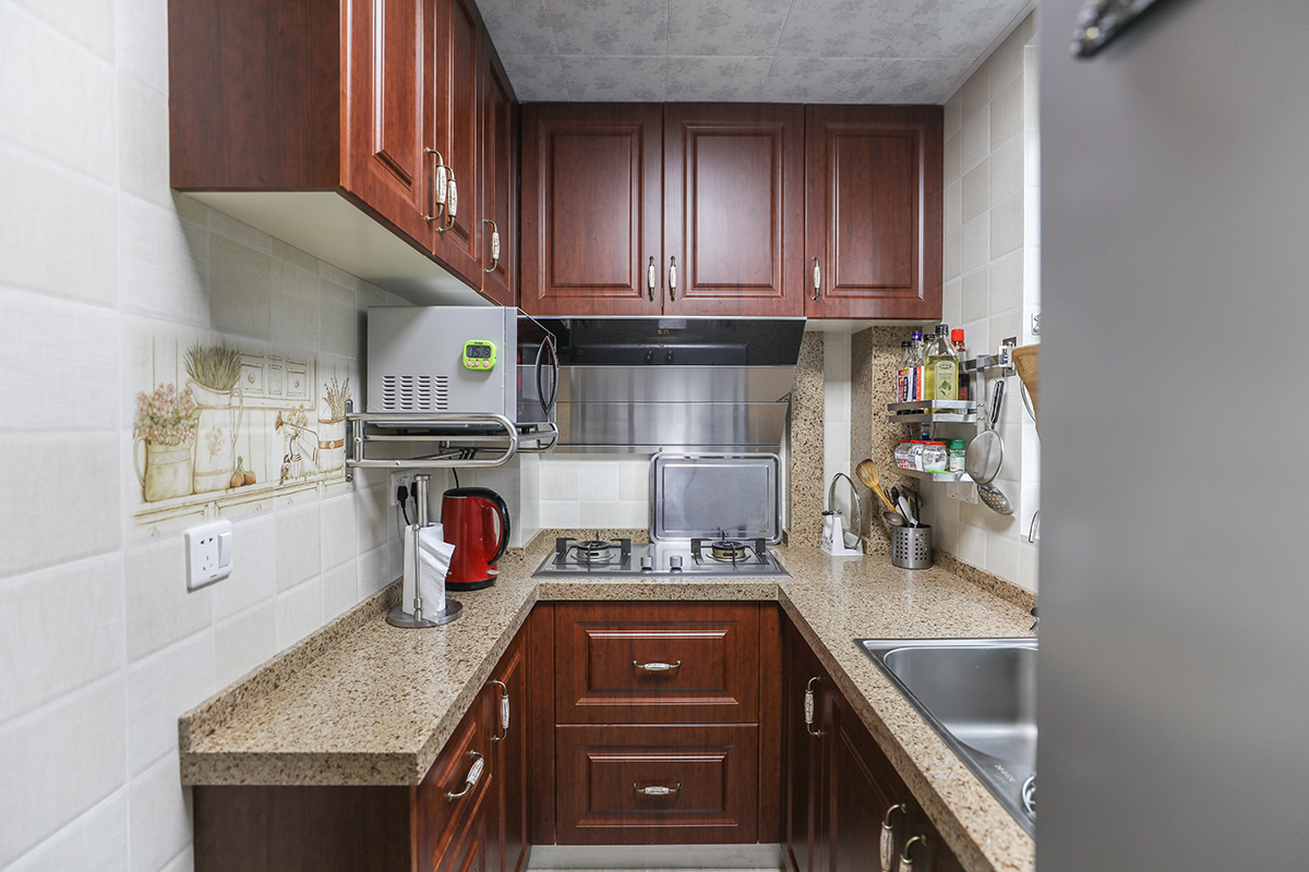厨房间的设计采用了U字型橱柜，在去掉中间走道的距离还可以做出一排置放电器的操作台面和储物柜，完全可以将厨房的物品归纳收藏，将厨房的空间利用到最大化。
