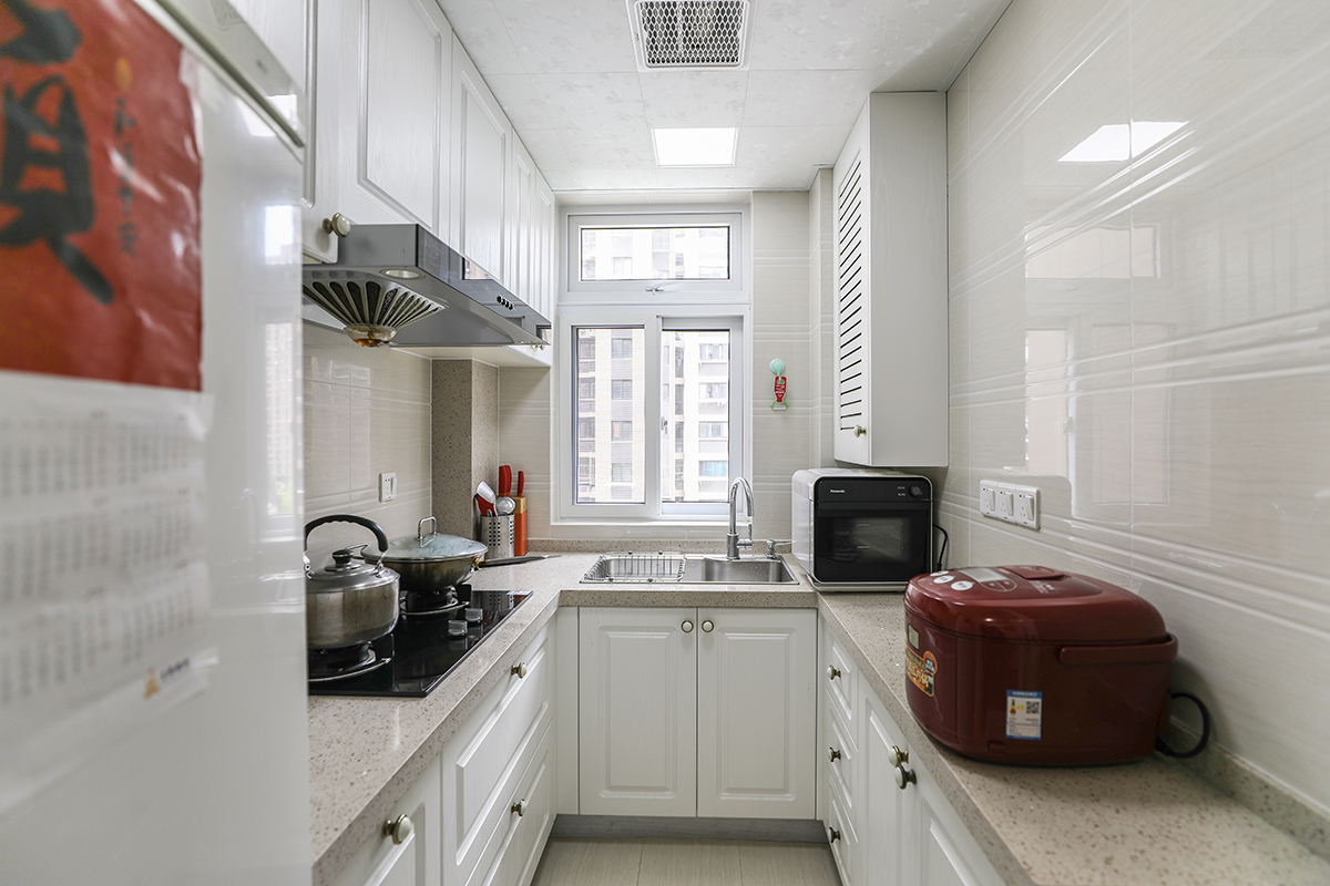 U型厨房的设计在功能上符合水槽、冰箱、灶台呈三角定位，五大分区的划分上也一目了然。米白色的大理石台面，搭配月白色的橱柜，使厨房给人感觉简洁明了。厨房的窗户采光及通风布局也很合理。
