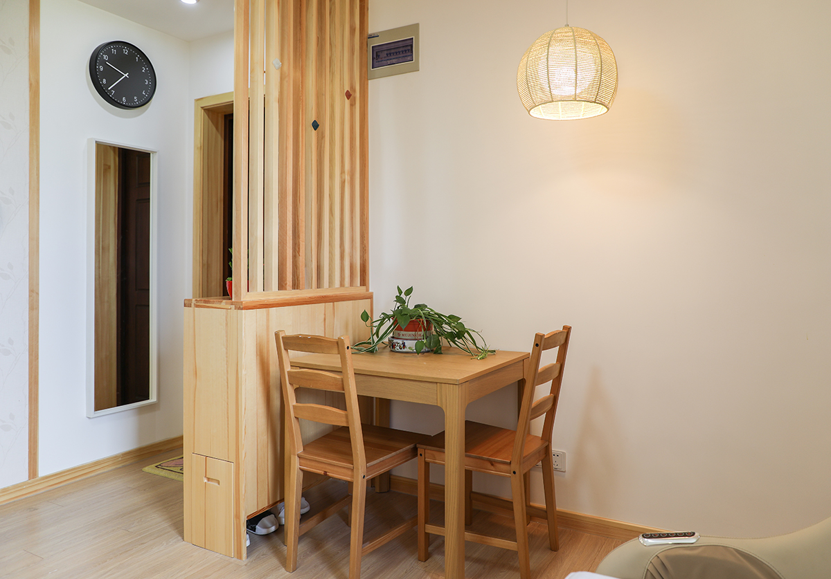 利用玄关划分出独立的餐厅区域，原木的小餐桌，日式风格的小吊灯，温馨舒适。
