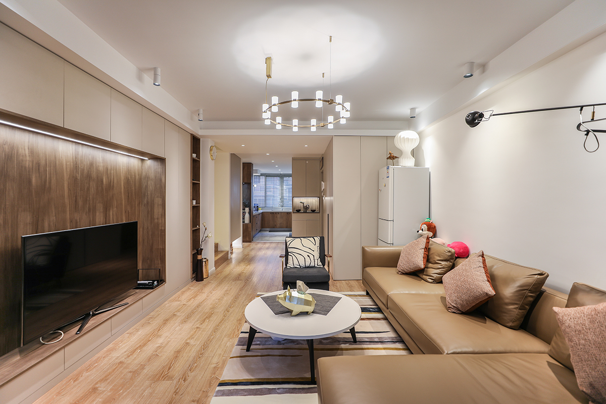 整个客厅采用了木色的地板，使得空间非常的简洁清爽，造型的无意中给客厅增添一处亮点，暖色的墙面和木纹的地板加以白色的木门使得简约元素非常的充足，得以空间的最大化。
